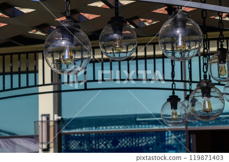 Charming outdoor lighting enhances the summer atmosphere at a vibrant cafe during sunny afternoon hours Charming outdoor lighting enhances the summer atmosphere at a vibrant cafe during sunny afternoon hours 119871403