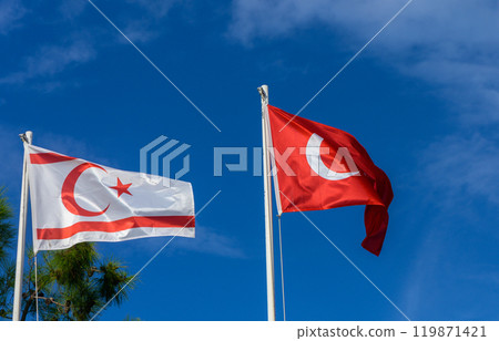 Flags of Turkish Republic of Northern Cyprus and Turkey waving against a bright blue sky in a serene atmosphere 119871421