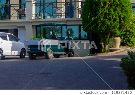 A green utility vehicle parked beside a modern building under the clear blue sky in a serene coastal setting during bright daylight A green utility vehicle parked beside a modern building under the clear blue sky in a serene coastal setting during bright daylight 119871450