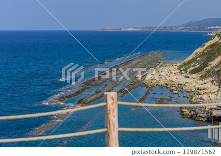 Majestic coastal view featuring rocky formations and calm blue waters along a sunlit shore in the afternoon 119871562