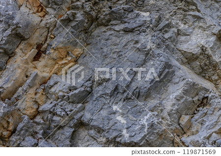 Rugged granite cliff face showcasing weathered textures and geological formations in a natural landscape under soft daylight 119871569