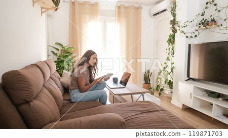 Serious woman reading diary in living room at home Serious woman reading diary in living room at home 119871703