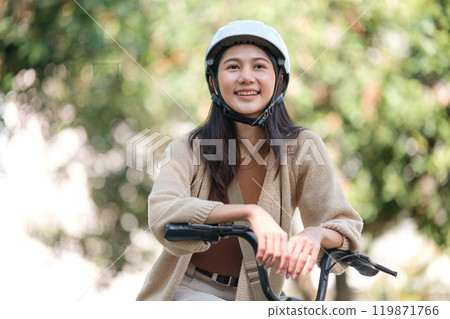 A woman is sitting on a bicycle wearing a helmet A woman is sitting on a bicycle wearing a helmet 119871766