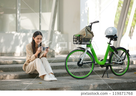A woman is sitting on a step with a green bicycle next to her A woman is sitting on a step with a green bicycle next to her 119871768