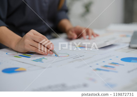 A woman is working on a graph with a pen on a table 119872731