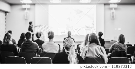 Speaker giving a talk in conference hall at business event. Rear view of unrecognizable people in audience at the conference hall. Business and entrepreneurship concept. Blue tones black and white 119873313
