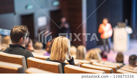 Business and entrepreneurship symposium. Female speaker giving a talk at business meeting. Audience in conference hall. Rear view of unrecognized participant in audience. Business and entrepreneurship symposium. Female speaker giving a talk at business meeting. Audience in conference hall. Rear view of unrecognized participant in audience. 119873338
