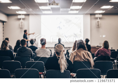 Speaker giving a talk in conference hall at business event. Rear view of unrecognizable people in audience at the conference hall. Business and entrepreneurship concept 119873371