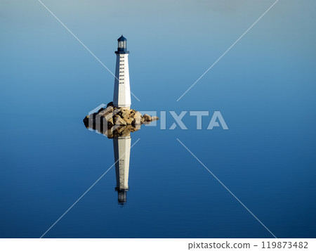 Automatic sea lighthouse reflecting in clear blue water Automatic sea lighthouse reflecting in clear blue water 119873482