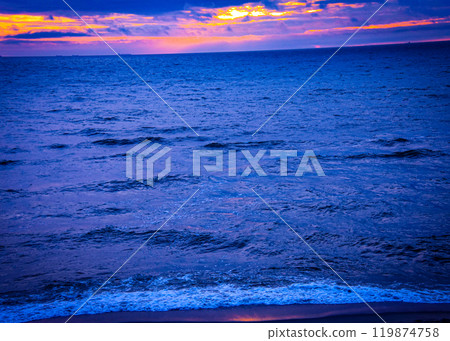 A beautiful blue ocean scene featuring a vibrant sunset in the background A beautiful blue ocean scene featuring a vibrant sunset in the background 119874758