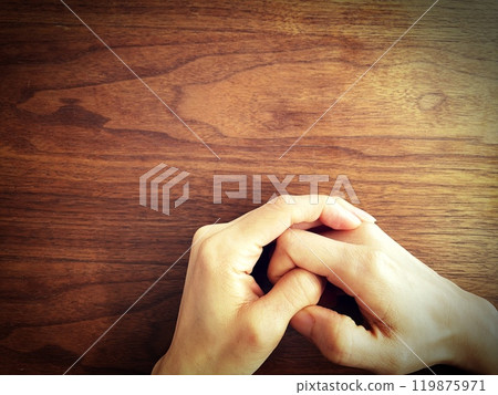 A woman's hand clenching her fist on a desk A woman's hand clenching her fist on a desk 119875971