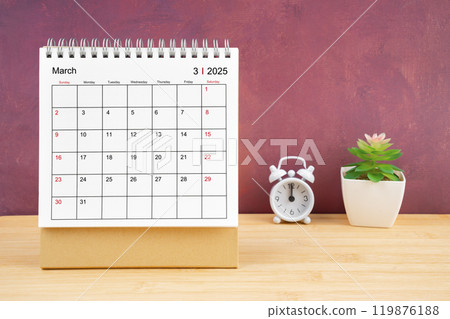March Monthly desk calendar for 2025 year and alarm clock on wooden table. 119876188