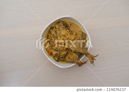 Fried fish with curry in a bowl on a wooden table. Fried fish with curry in a bowl on a wooden table. 119876237