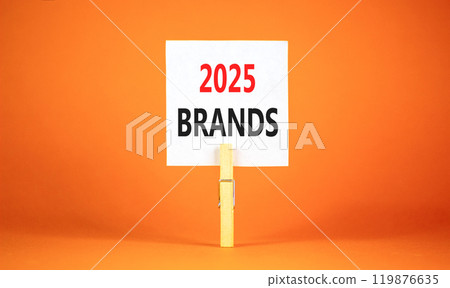 Planning 2025 brands new year symbol. Concept words 2025 Brands on beautiful white paper on wooden clothespin. Beautiful orange background. Business 2025 brands new year concept. Copy space. Planning 2025 brands new year symbol. Concept words 2025 Brands on beautiful white paper on wooden clothespin. Beautiful orange background. Business 2025 brands new year concept. Copy space. 119876635