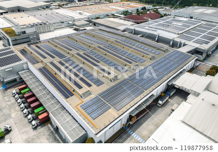 Solar-powered warehouse facility with freight trucks at loading docks. Eco-friendly logistics and efficient cargo transportation. Solar panels and sustainable energy concept in distribution center. 119877958