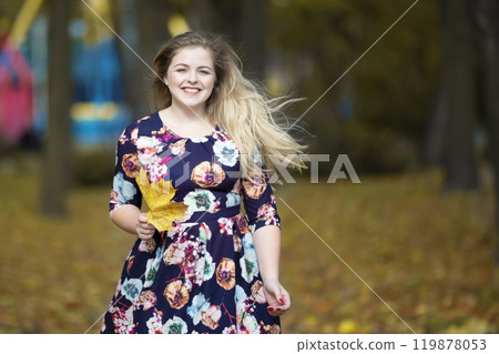 Happy blonde girl in autumn park with maple leaves. Happy blonde girl in autumn park with maple leaves. 119878053