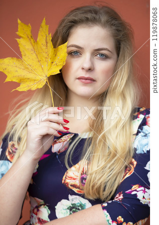 A beautiful blonde girl with blue eyes is holding a maple leaf. A beautiful blonde girl with blue eyes is holding a maple leaf. 119878068