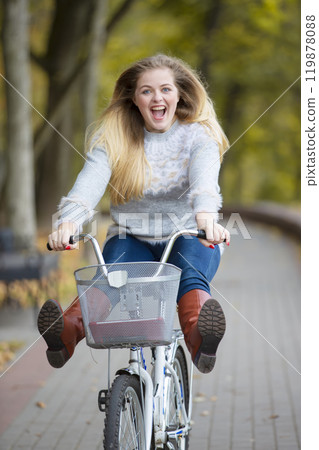 Young beautiful woman rides a bicycle in the autumn park. 119878088