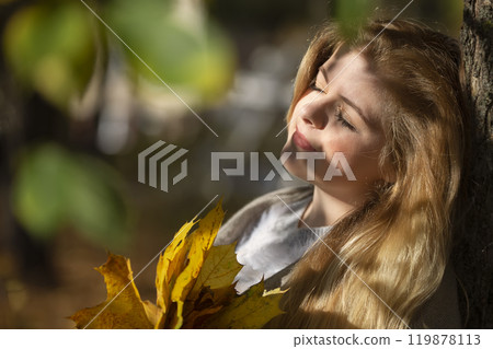 Beautiful young woman with yellow leaves in the autumn park. 119878113