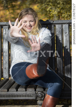 Beautiful young woman in an autumn park sits on a bench. Beautiful young woman in an autumn park sits on a bench. 119878127