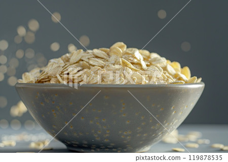Oat flakes in a bowl on a gray background with bokeh 119878535