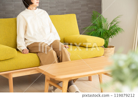 Middle-aged to senior woman relaxing on the sofa in the living room 119879212