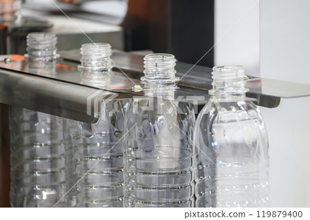 The empty drinking water bottles on the conveyor belt for filling process. The empty drinking water bottles on the conveyor belt for filling process. 119879400