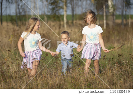 Happy family: sisters and little brother on a summer meadow. Happy family: sisters and little brother on a summer meadow. 119880429