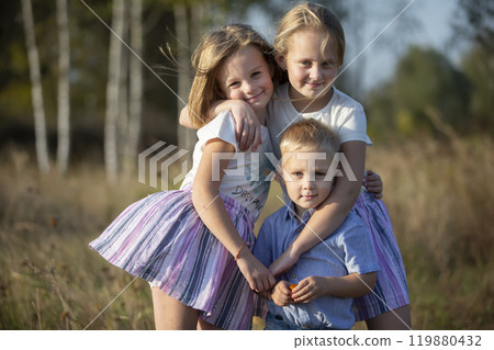 Little brother and two sisters are looking at the camera. Little brother and two sisters are looking at the camera. 119880432