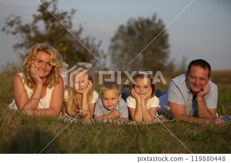Happy family: mother, father, children, son and daughters in nature. A beautiful family lies on the grass in the park. 119880448