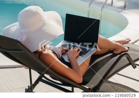 Woman Working Remotely by Poolside on Laptop 119880529
