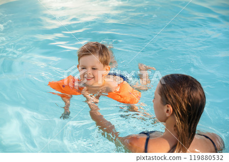 Smiling Child Learning to Swim in Pool 119880532