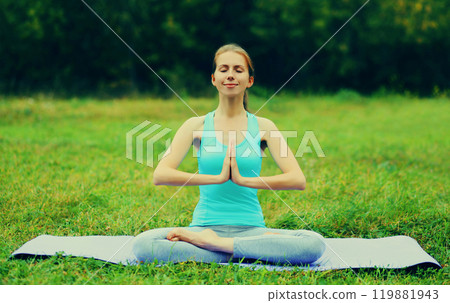 Young woman doing yoga exercises on a mat on the grass in summer park Young woman doing yoga exercises on a mat on the grass in summer park 119881943