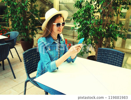 Portrait of smiling young woman sitting at table in cafe with phone Portrait of smiling young woman sitting at table in cafe with phone 119881983