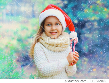 Christmas child little girl in santa red hat with sweet lollipop cane Christmas child little girl in santa red hat with sweet lollipop cane 119882002