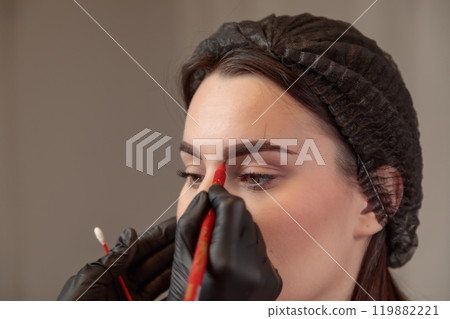 Beautician drawing eyebrow shape on woman's face for microblading treatment 119882221
