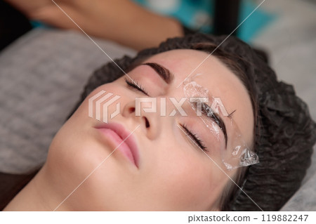 Beautician applying permanent makeup on eyebrows of client Beautician applying permanent makeup on eyebrows of client 119882247