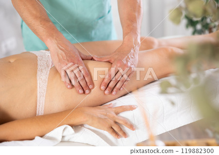 massage therapist doing a leg massage massage therapist doing a leg massage 119882300