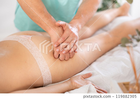 Woman lies and enjoys during anti-cellulite massage in buttocks Woman lies and enjoys during anti-cellulite massage in buttocks 119882305