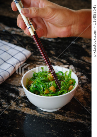 Wakame salad in a bowl and bamboo sticks Wakame salad in a bowl and bamboo sticks 119882545