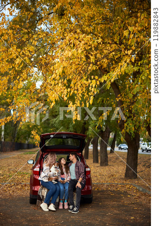 Happy parents with daughter and cute dog Jack Russel terrier sitting in car trunk on autumn day Happy parents with daughter and cute dog Jack Russel terrier sitting in car trunk on autumn day 119882843