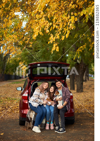 Happy parents with daughter and cute dog Jack Russel terrier sitting in car trunk on autumn day Happy parents with daughter and cute dog Jack Russel terrier sitting in car trunk on autumn day 119882865