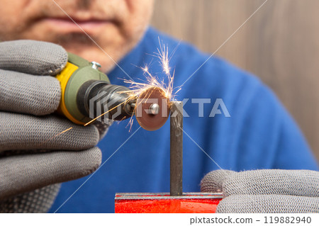 hands of a male mechanic processing metal with an engraving drill in a workshop hands of a male mechanic processing metal with an engraving drill in a workshop 119882940