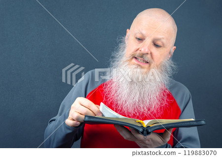 venerable christian man with a large gray beard focused on reading the bible venerable christian man with a large gray beard focused on reading the bible 119883070