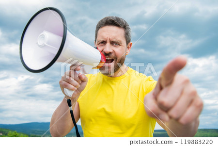 man in yellow shirt shout in loudspeaker on sky background. announcement man in yellow shirt shout in loudspeaker on sky background. announcement 119883220