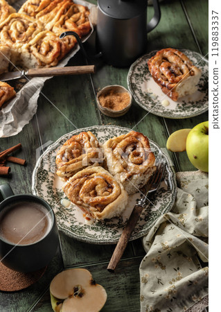 Autumn apple cinnamon rolls with frosting on green wooden background. Seasonal autumn homemade pastry cinnabons for breakfast 119883337