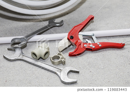 On the floor, there is a pair of metal wrenches and a pipe cutter 119883443