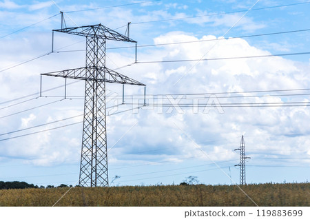 Electricity concept. High voltage power line pylons, electrical tower on a green field with blue sky. Electricity concept. High voltage power line pylons, electrical tower on a green field with blue sky. 119883699