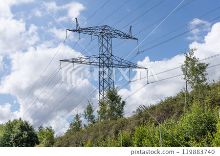 Electricity concept. Electricity concept. High voltage power line pylons, electrical tower on a green field with blue sky. Electricity concept. Electricity concept. High voltage power line pylons, electrical tower on a green field with blue sky. 119883740