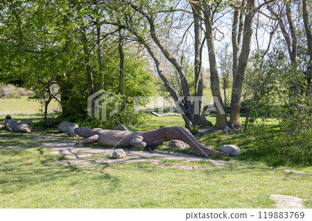 Summer park for outdoor activities with a bench and a large wooden crocodile. 119883769
